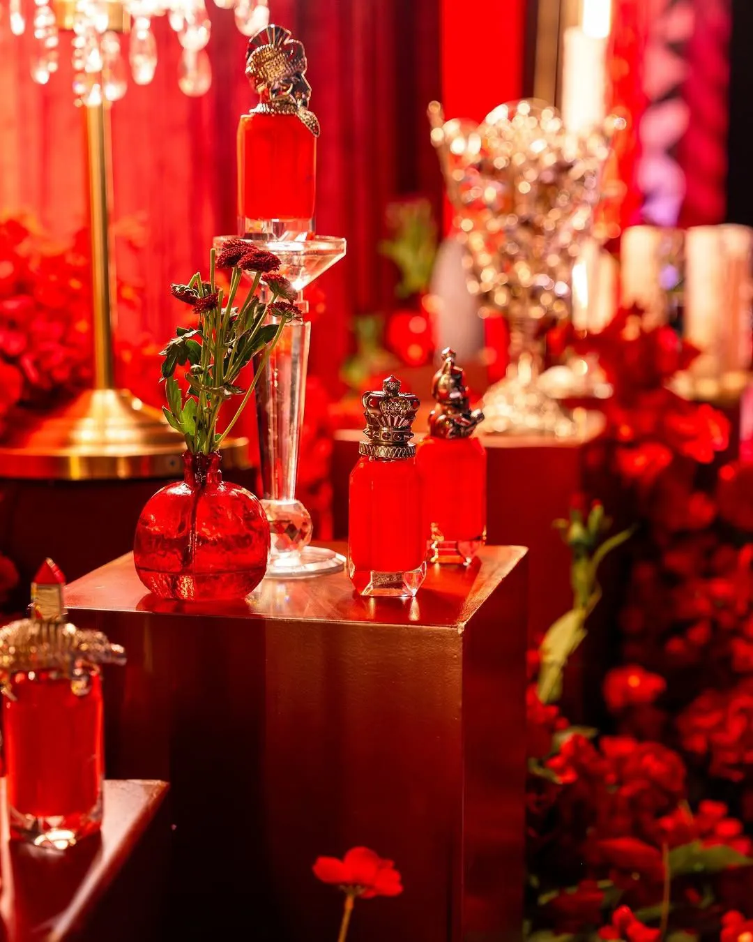 Ruby perfume bottles, glass vases and red blooms on a gift table