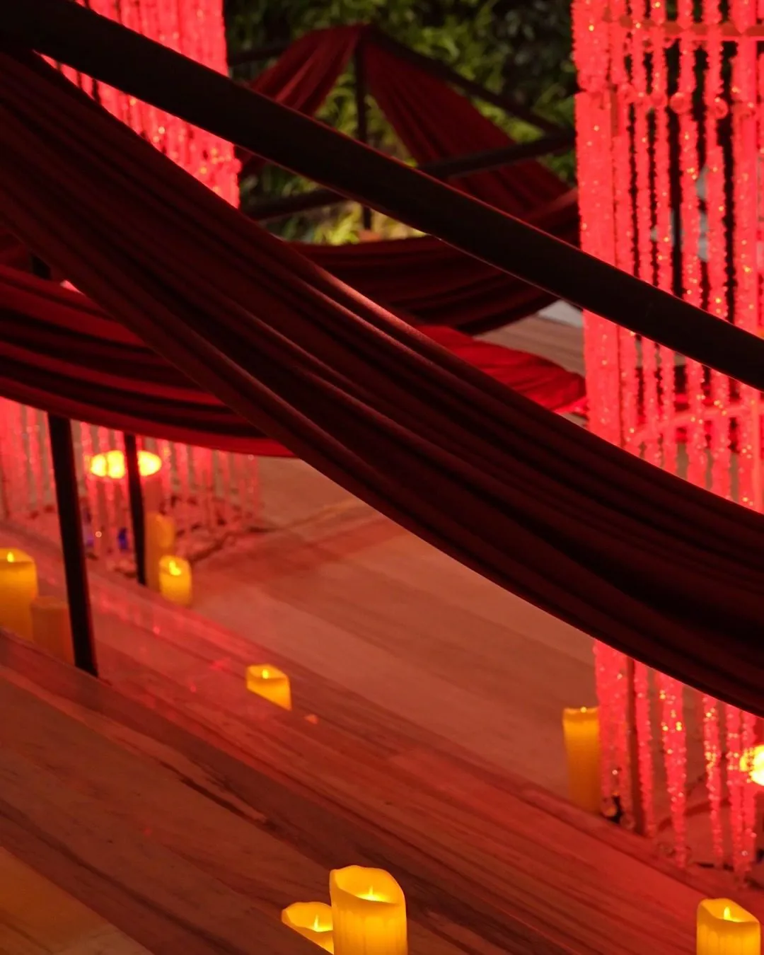 Red drapery and beaded column over candlelit stairs