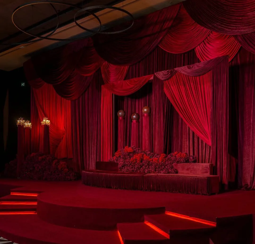 Crimson velvet wedding stage with lit steps and a black-and-white checkered aisle