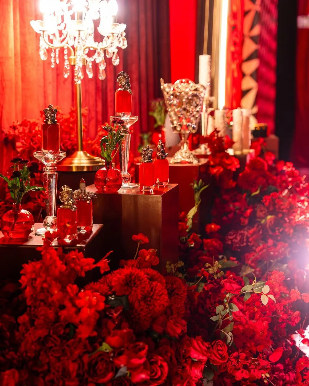 Perfume corner with red bottles on gold pedestals under a crystal chandelier