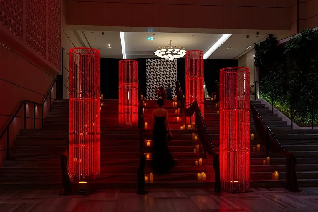 Candlelit staircase entrance framed by tall red beaded pillars