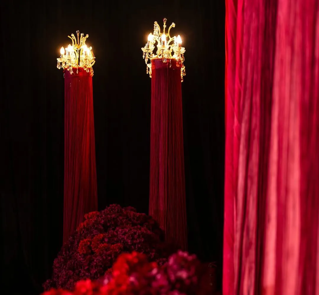 Gilded chandelier columns rising over deep red flowers